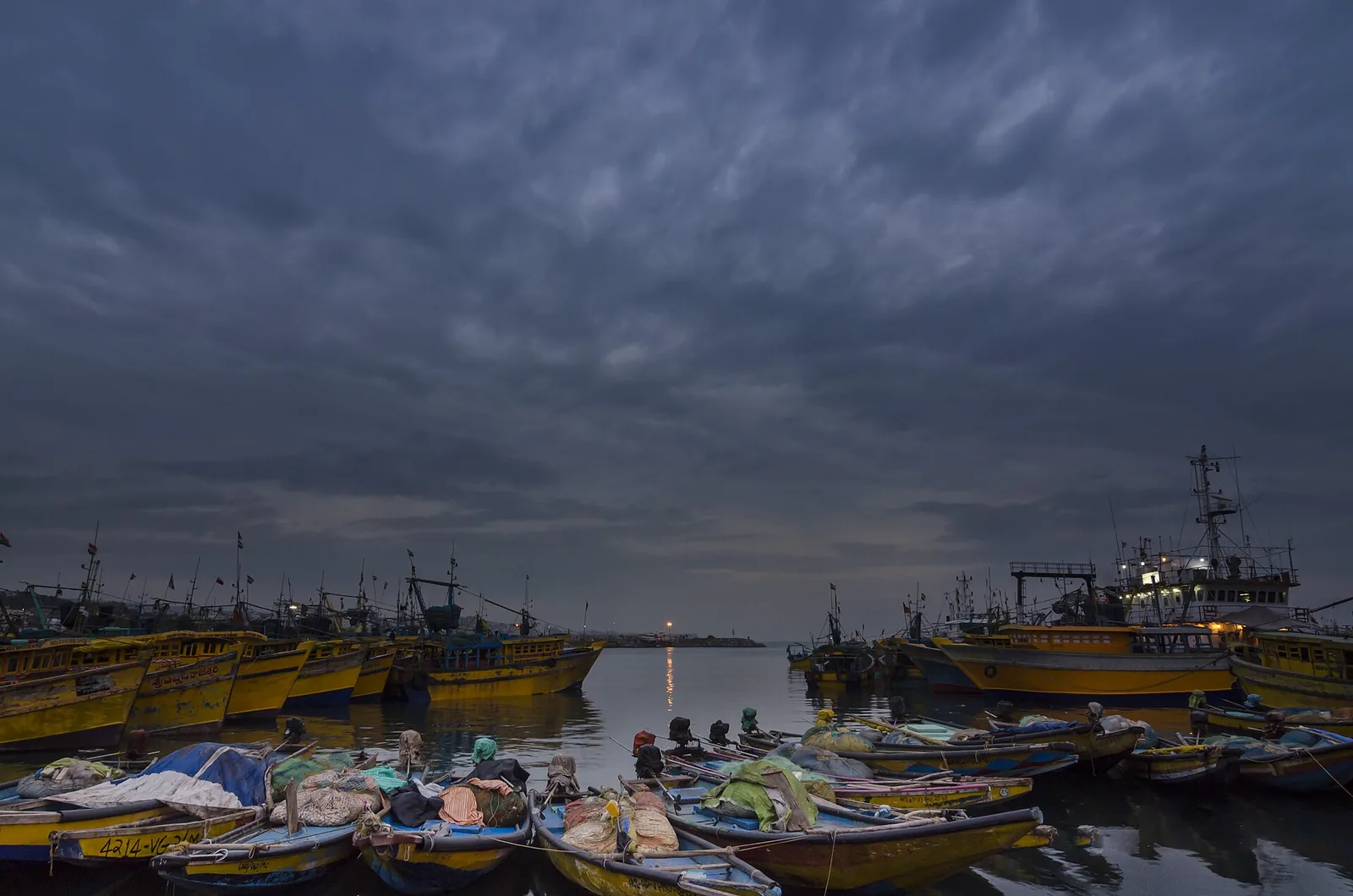 Fishing boats at Visakhapatnam harbour under a dark sky before the cyclone