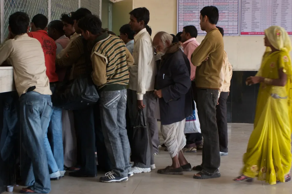 Passengers at a railway reservation counter in India, where train ticket insurance starts 27 October