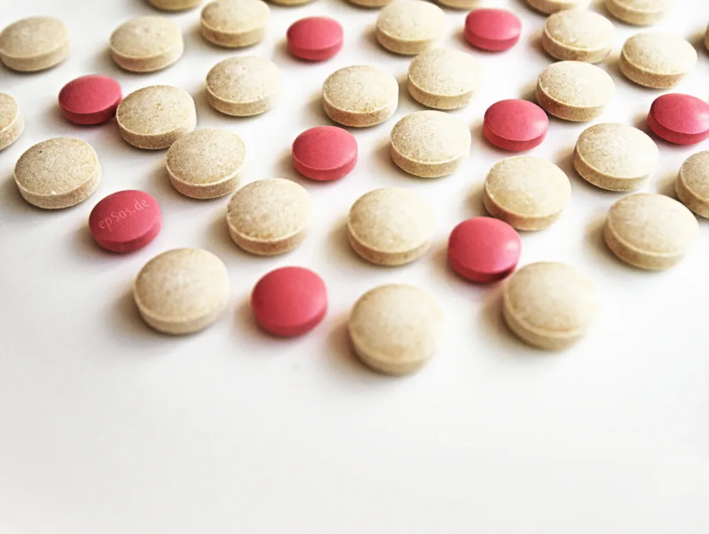 Pink and beige tablets on a white surface, illustrating cancer drug mark-ups