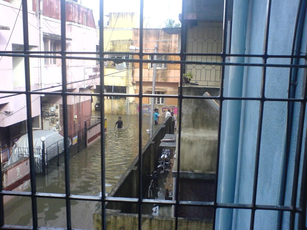 Waterlogged residential lane in Chennai seen through a window during Tamil Nadu rain
